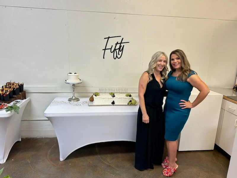 Angela and a guest posing beside the birthday cakes.