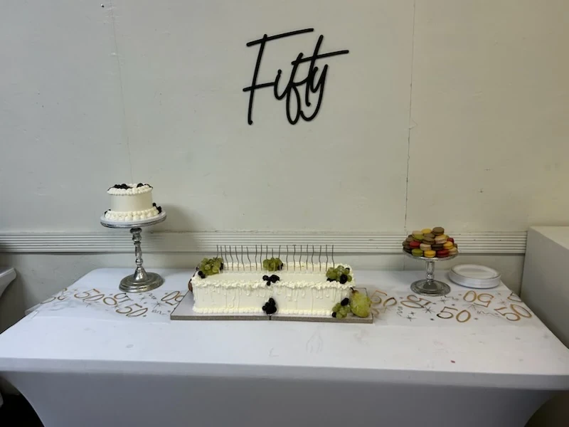 Birthday cakes and macarons arranged beneath the Fifty sign.