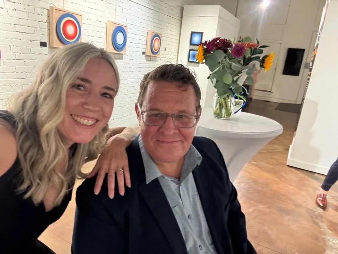Two guests smiling for a selfie near the circular paintings.