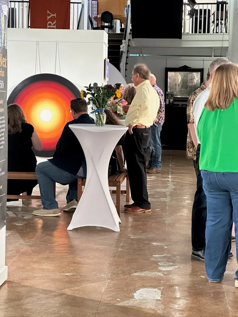 Guests gathered near the large circular sun painting.