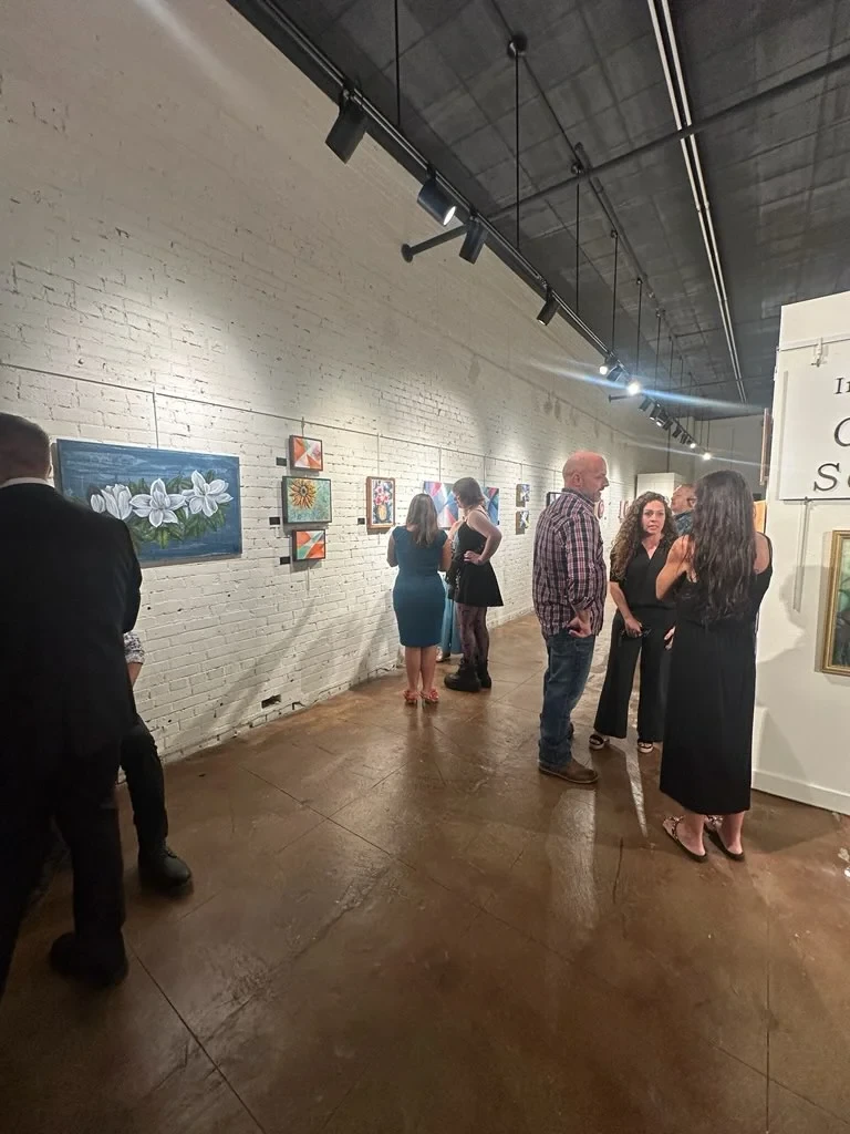 Guests visiting along the gallery wall of paintings.